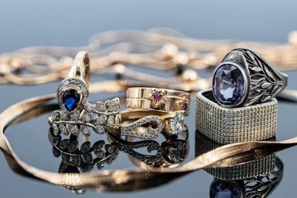 Anillos con piedras azules y moradas junto a cadenas doradas